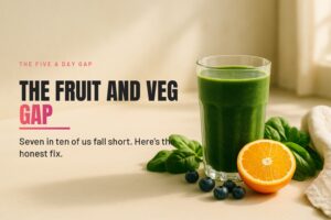 A tall glass of green smoothie with fresh spinach, blueberries and orange on a clean sunlit counter.