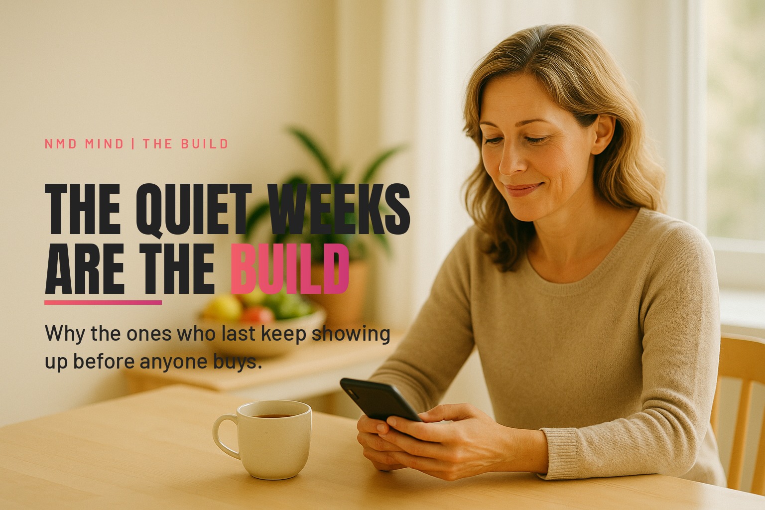 A woman doing her fifteen minutes of online business at a bright kitchen table early in the morning, cup of tea beside her, phone in hand.
